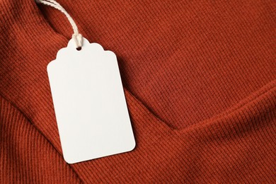Photo of Cardboard tag on orange garment, top view