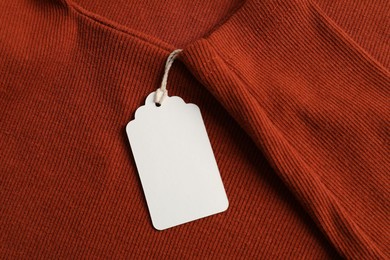 Photo of Cardboard tag on orange garment, top view