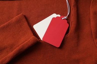 Photo of Cardboard tags on orange garment, top view