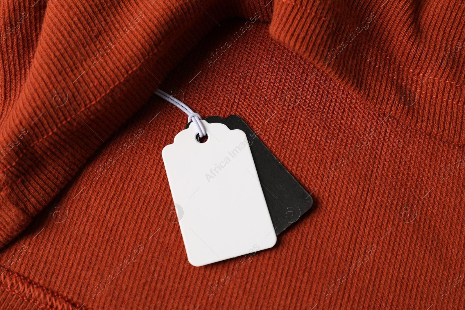 Cardboard tags on orange garment, above view Photo of Cardboard tags on orange garment, above view