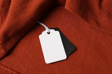 Photo of Cardboard tags on orange garment, above view