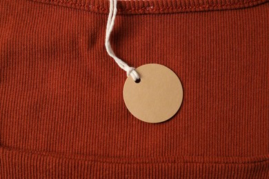 Photo of Cardboard tag on orange garment, top view