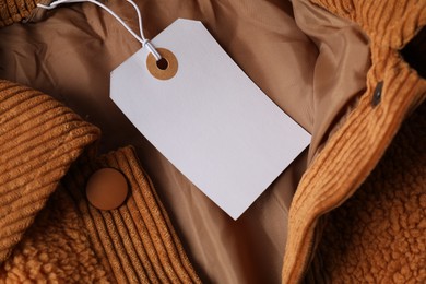Photo of Cardboard tag on brown garment, top view
