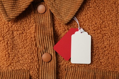 Photo of Cardboard tags on brown garment, top view