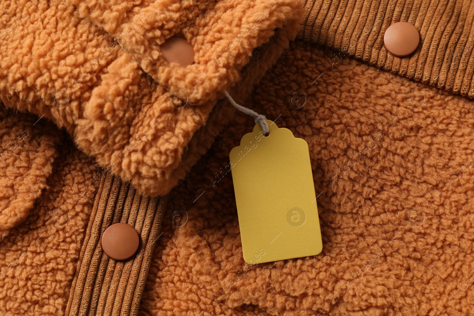 Cardboard tag on brown garment, top view Photo of Cardboard tag on brown garment, top view