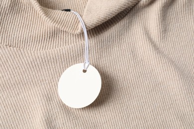 Photo of Cardboard tag on beige sweater, top view