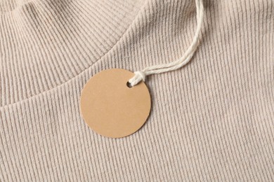 Photo of Cardboard tag on beige sweater, top view