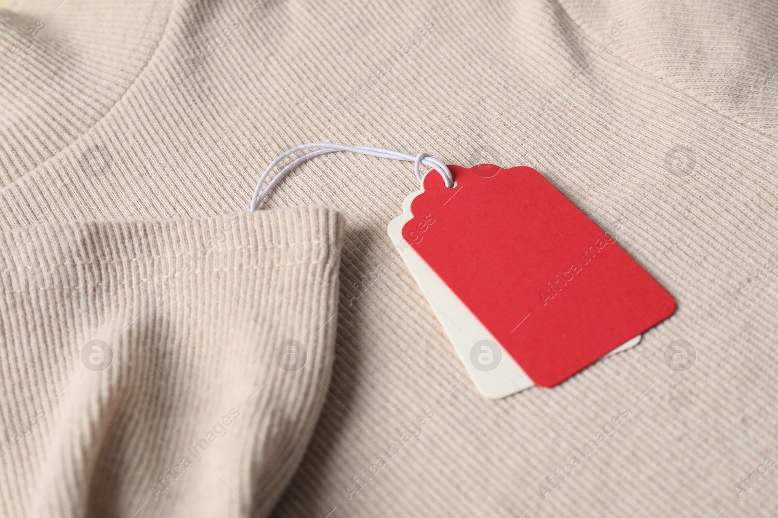 Cardboard tags on beige sweater, closeup view Photo of Cardboard tags on beige sweater, closeup view