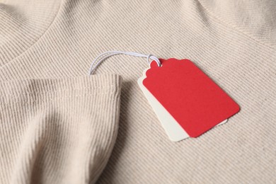 Photo of Cardboard tags on beige sweater, closeup view
