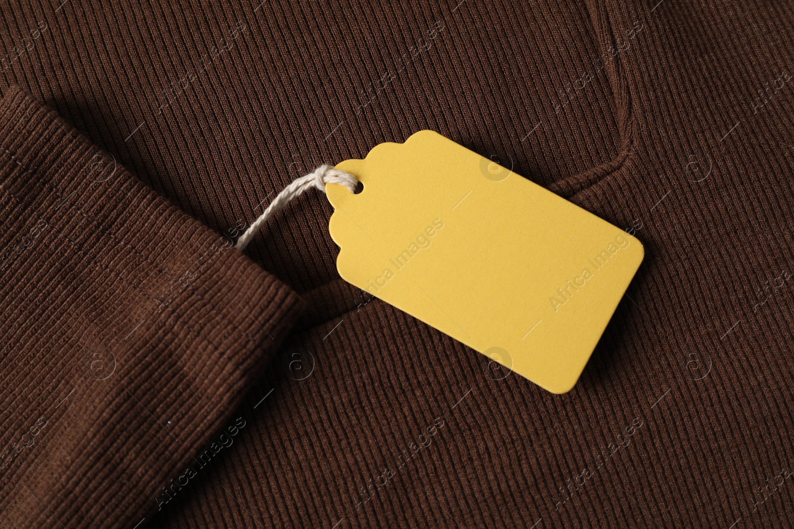Cardboard tag on brown garment, top view Photo of Cardboard tag on brown garment, top view