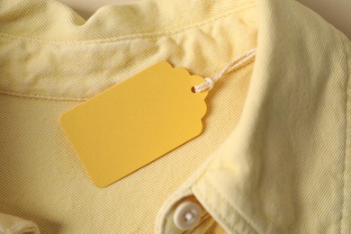 Photo of Cardboard tag on pale yellow shirt, top view