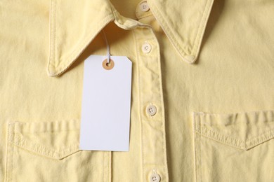Photo of Cardboard tag on pale yellow shirt, top view