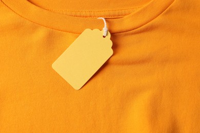 Photo of Cardboard tag on orange garment, top view