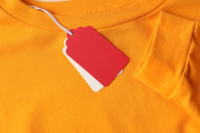 Photo of Cardboard tags on orange garment, top view