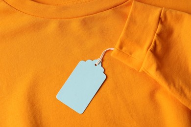 Photo of Cardboard tag on orange garment, top view