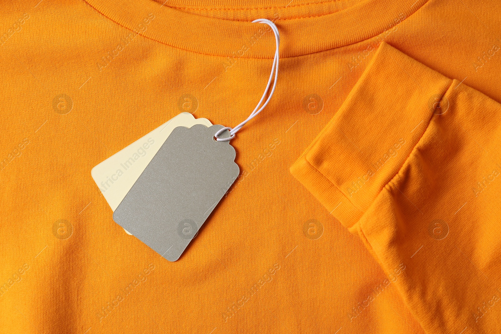 Cardboard tags on orange garment, top view Photo of Cardboard tags on orange garment, top view