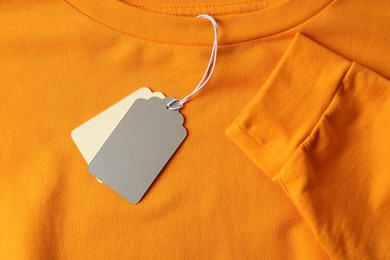 Photo of Cardboard tags on orange garment, top view