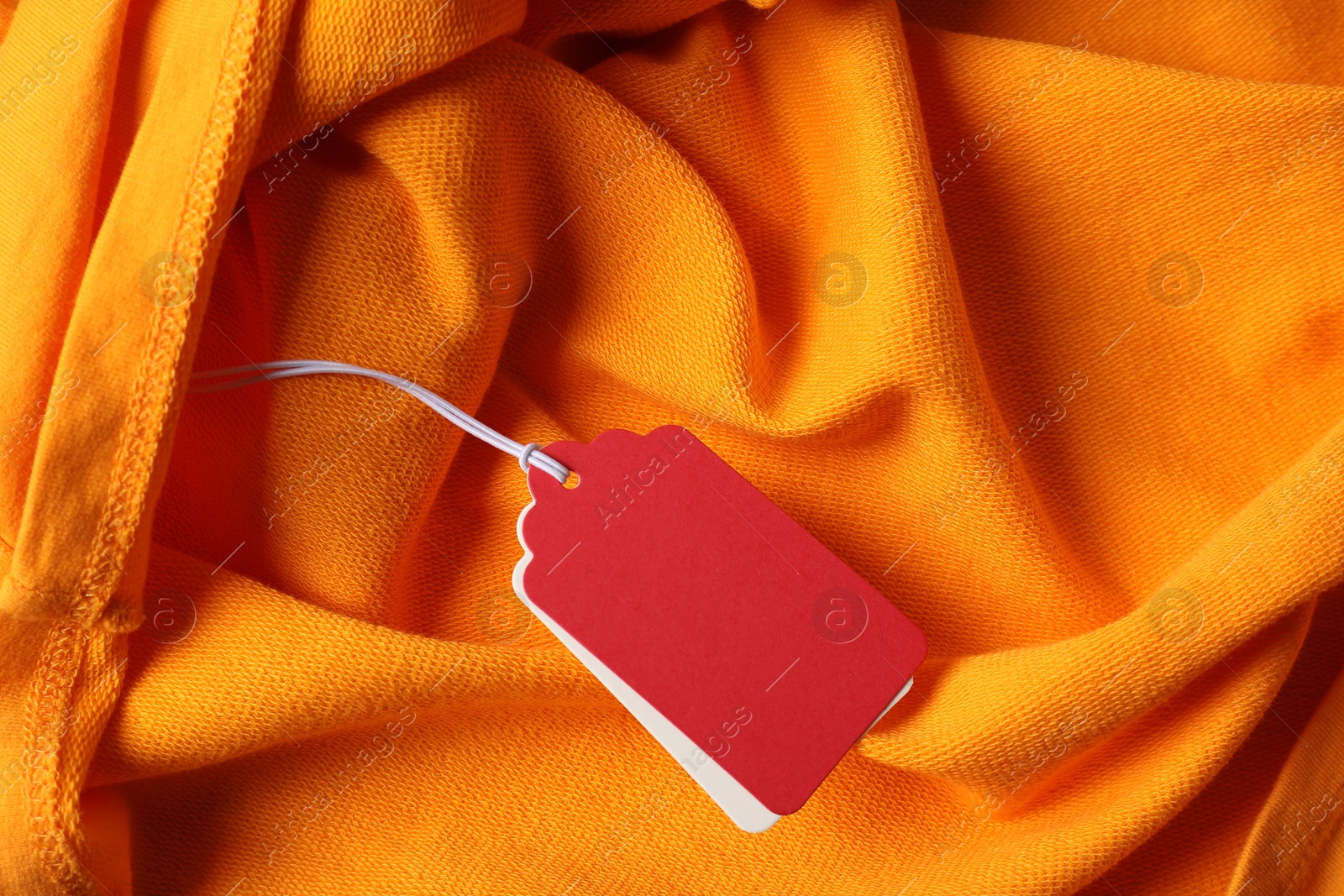 Cardboard tags on orange garment, top view Photo of Cardboard tags on orange garment, top view