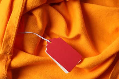Photo of Cardboard tags on orange garment, top view