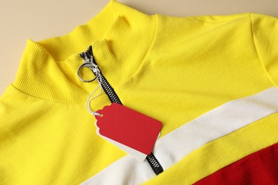 Photo of Colorful garment with tags on beige background, top view