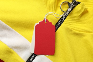 Photo of Cardboard tags on colorful garment, top view