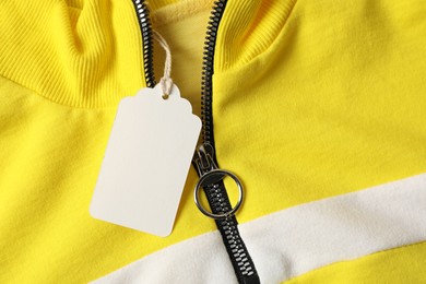 Photo of Cardboard tag on colorful garment, top view
