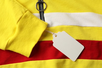 Photo of Cardboard tag on colorful garment, top view