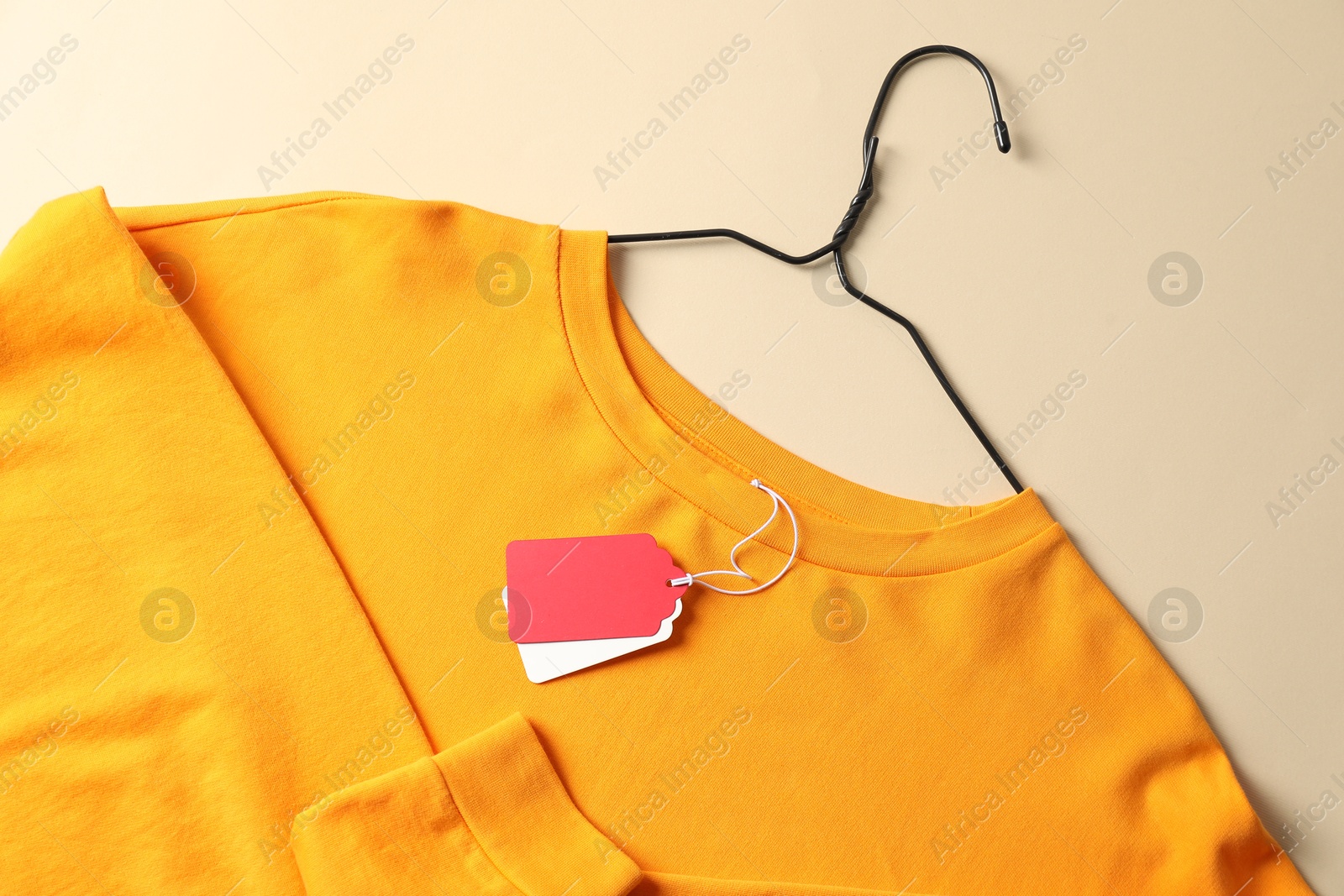 Orange garment with tags on beige background, top view Photo of Orange garment with tags on beige background, top view