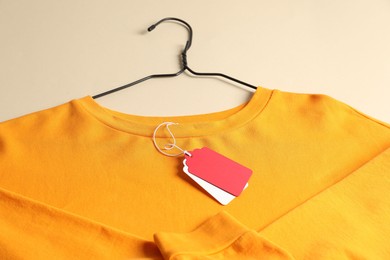 Photo of Orange garment with tags on beige background, above view