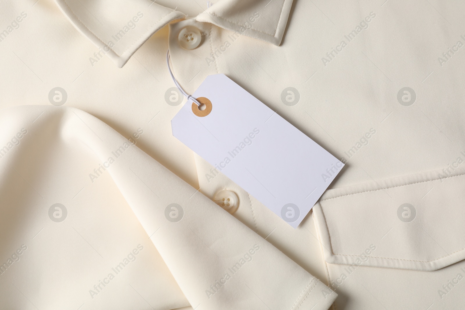 Cardboard tag on beige shirt, top view Photo of Cardboard tag on beige shirt, top view