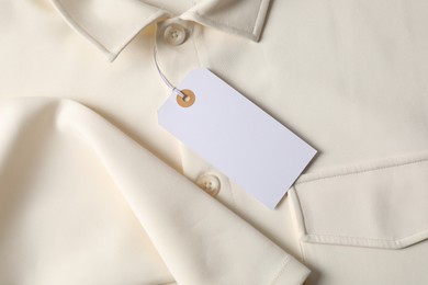 Photo of Cardboard tag on beige shirt, top view