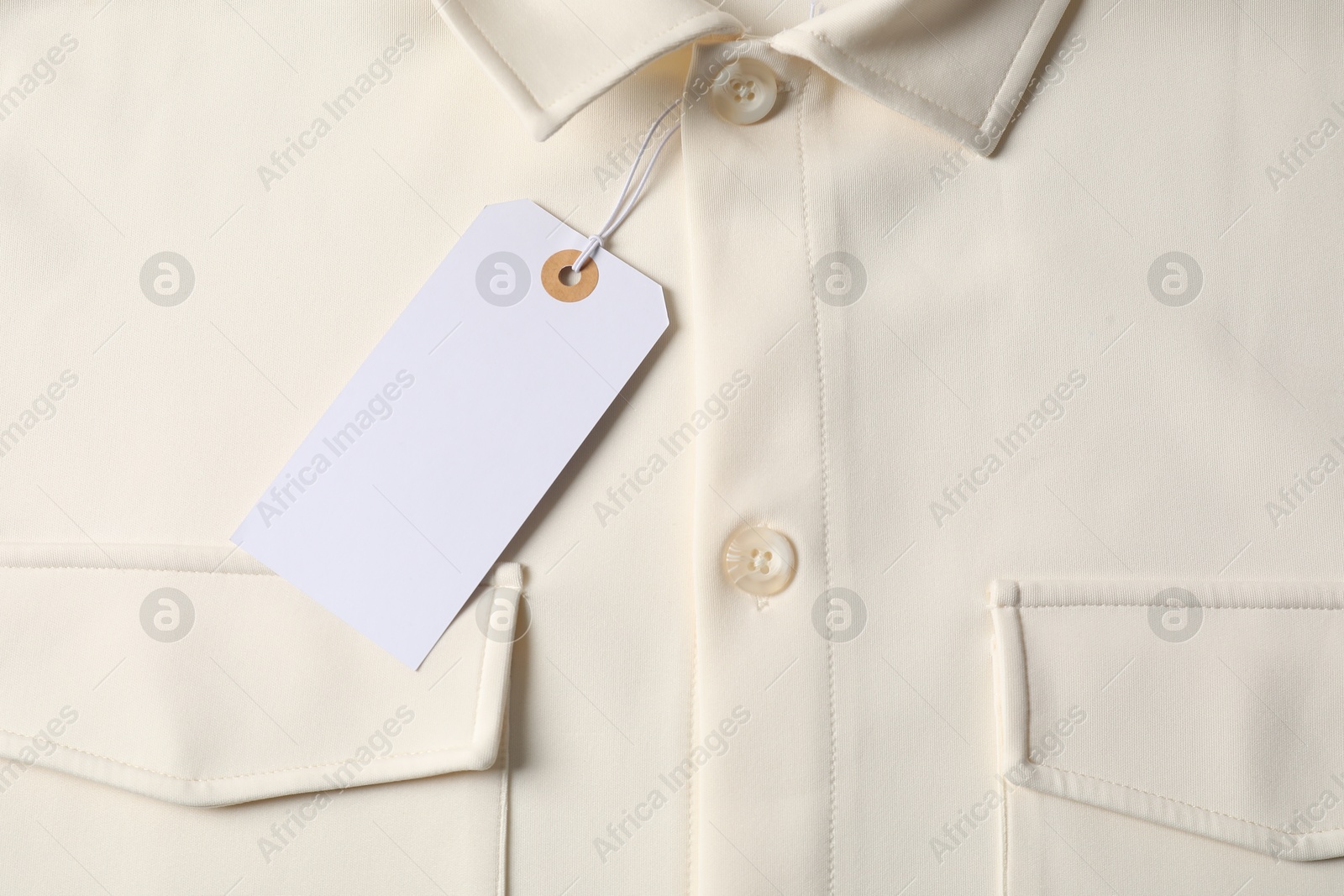 Cardboard tag on beige shirt, top view Photo of Cardboard tag on beige shirt, top view