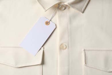 Photo of Cardboard tag on beige shirt, top view