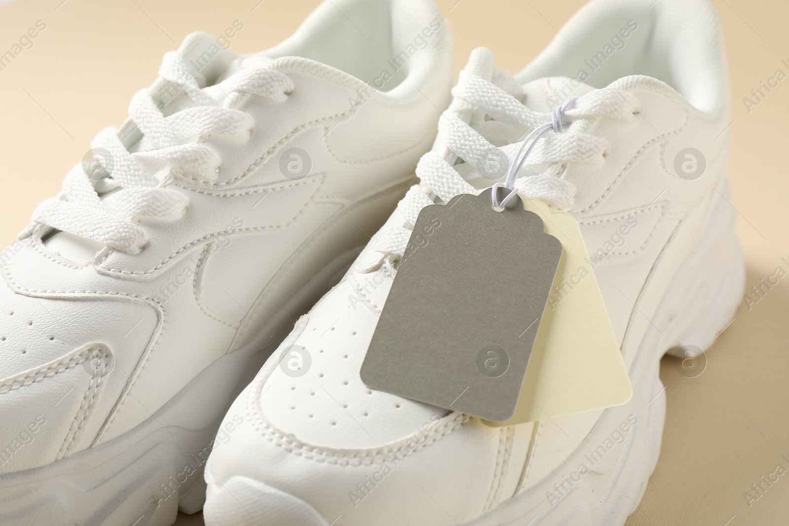 Pair of sneakers with tags on beige background, closeup Photo of Pair of sneakers with tags on beige background, closeup