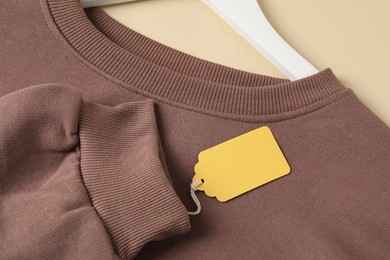 Photo of Brown garment with tag on beige background, above view