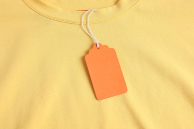 Photo of Cardboard tag on yellow garment, top view