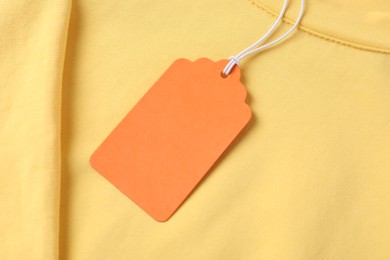 Photo of Cardboard tag on yellow garment, top view
