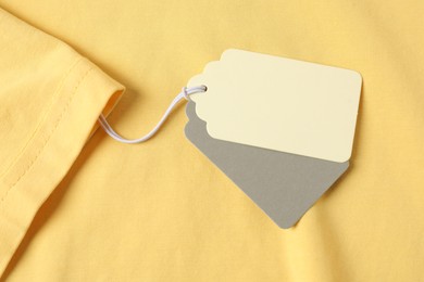 Photo of Cardboard tags on yellow garment, top view