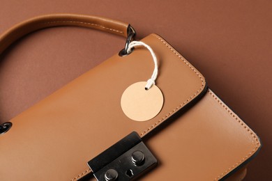 Photo of Leather bag with tag on brown background, above view