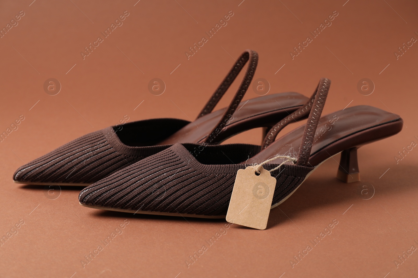 Elegant shoes with tag on brown, closeup Photo of Elegant shoes with tag on brown, closeup