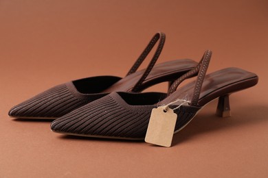 Photo of Elegant shoes with tag on brown, closeup