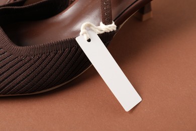 Photo of Elegant shoe with tag on brown, closeup