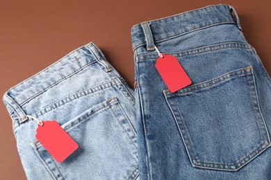 Photo of Jeans with tags on brown background, top view