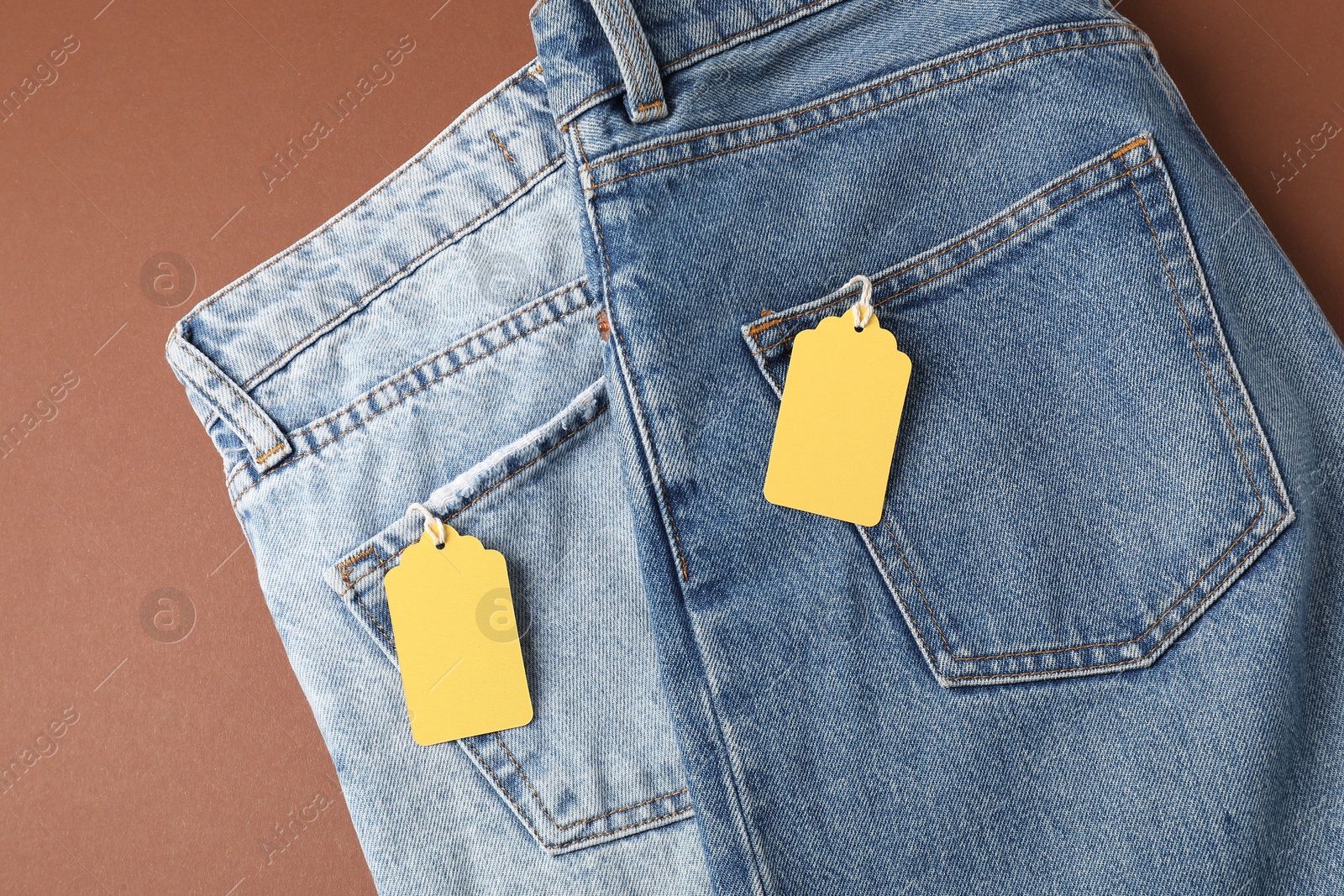 Jeans with tags on brown background, top view Photo of Jeans with tags on brown background, top view