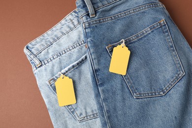 Photo of Jeans with tags on brown background, top view