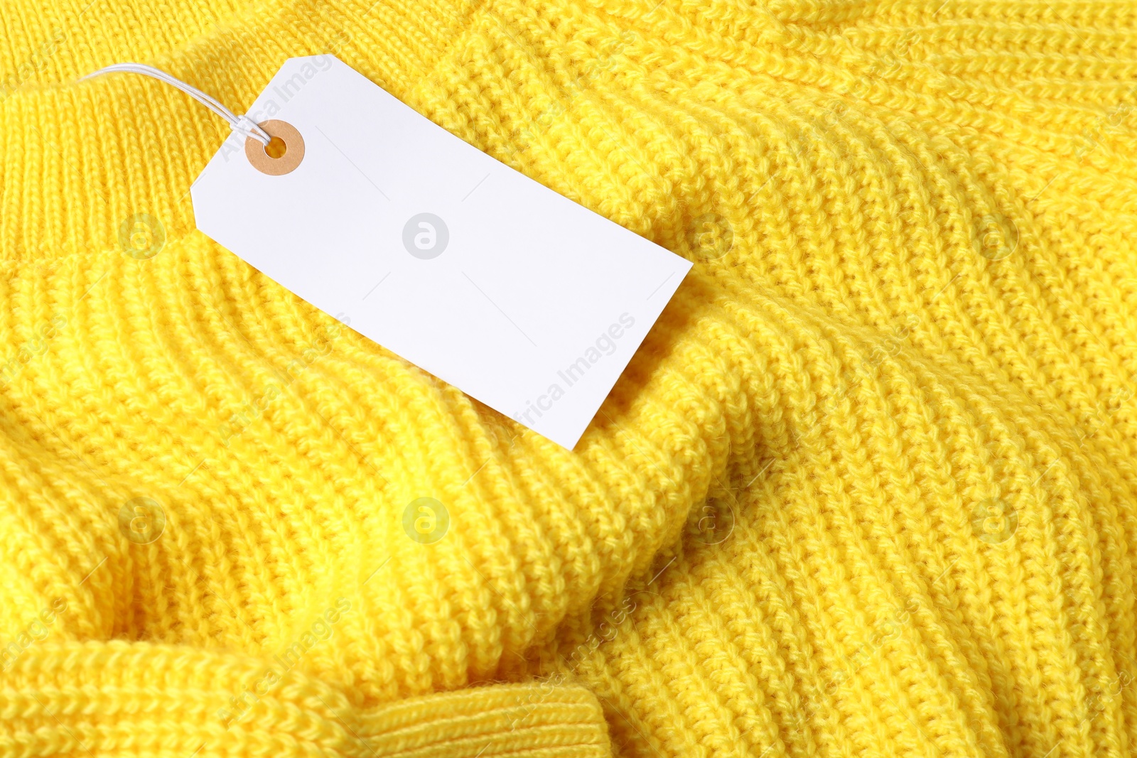 Cardboard tag on yellow knitted sweater, above view Photo of Cardboard tag on yellow knitted sweater, above view