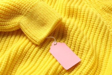 Photo of Cardboard tag on yellow knitted sweater, above view