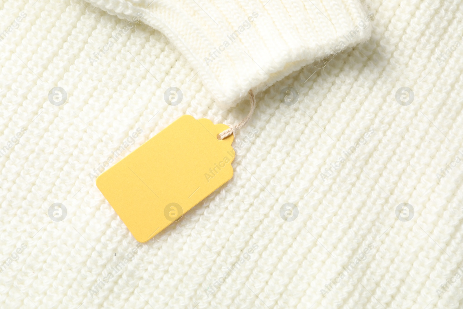 Cardboard tag on white knitted sweater, top view Photo of Cardboard tag on white knitted sweater, top view