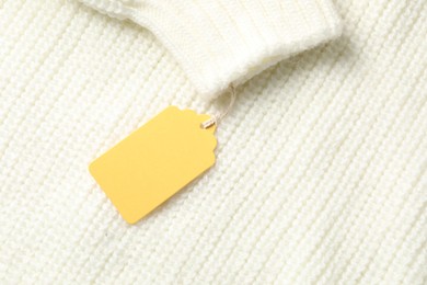 Photo of Cardboard tag on white knitted sweater, top view