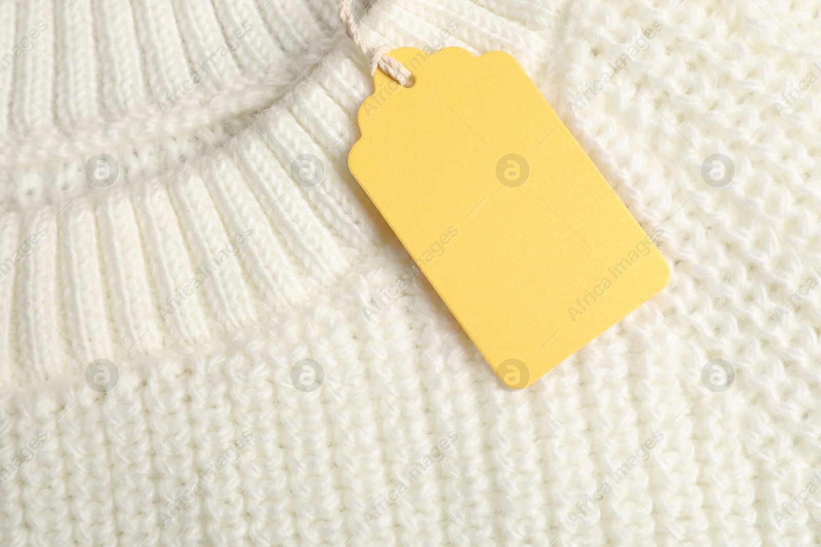 Cardboard tag on white knitted sweater, top view Photo of Cardboard tag on white knitted sweater, top view